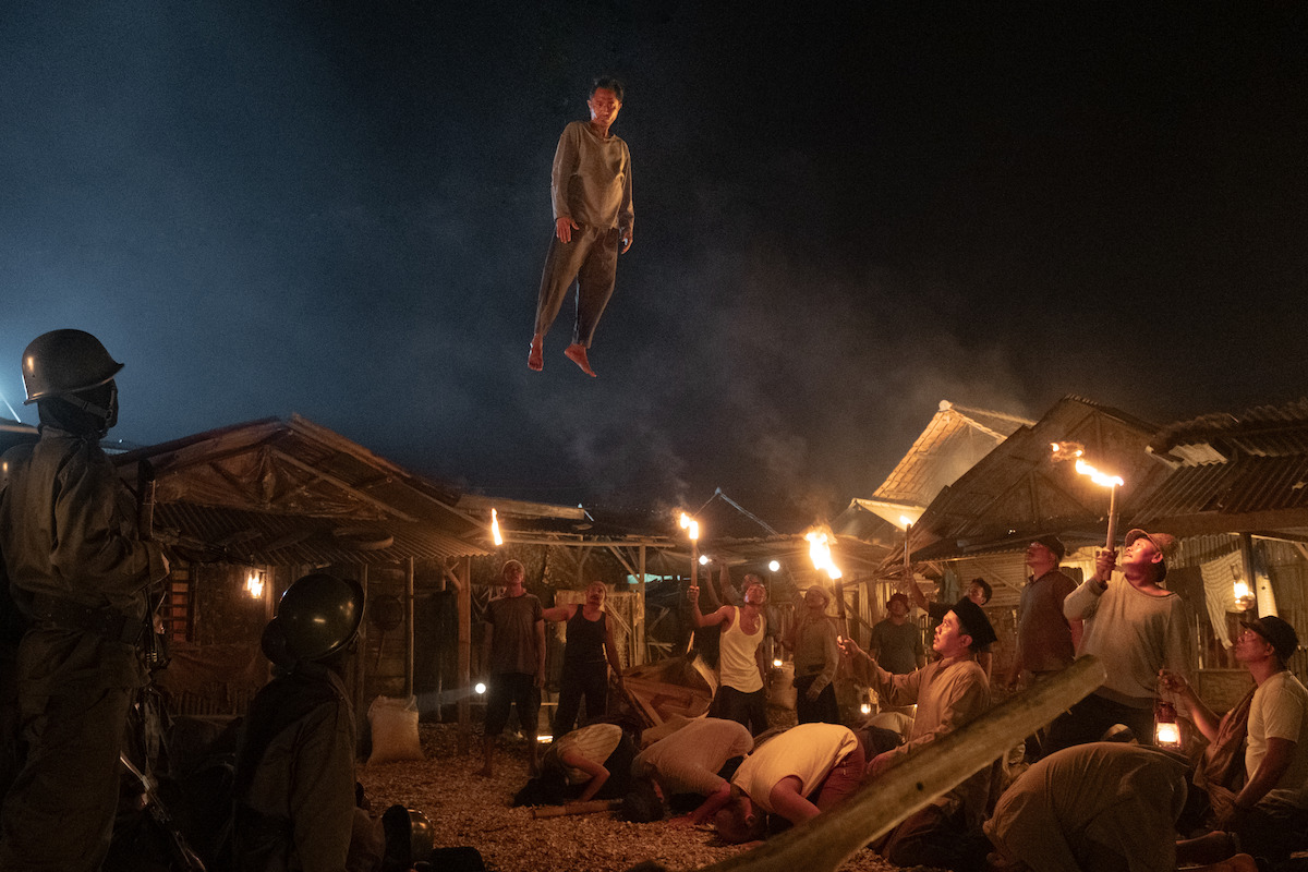 a man levitates above the village below