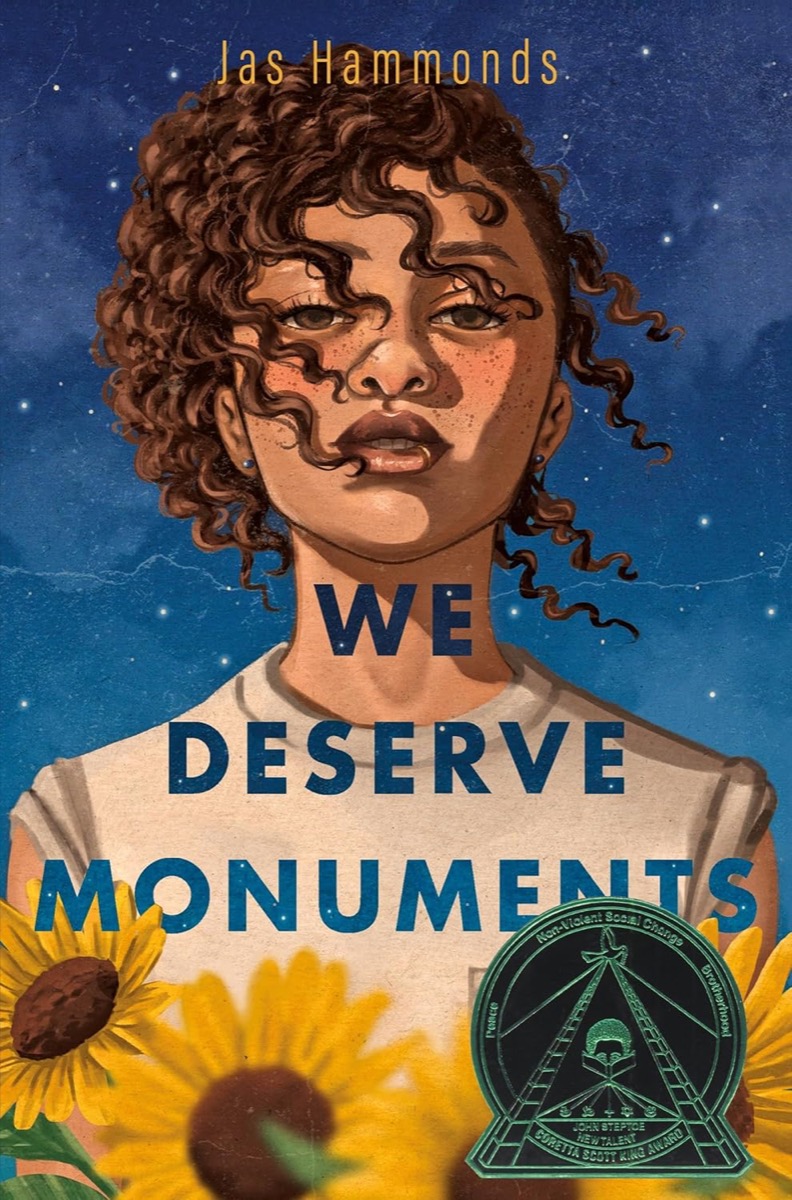 Cover art for "We Deserve Monuments" showing a young woman standing above sunflowers