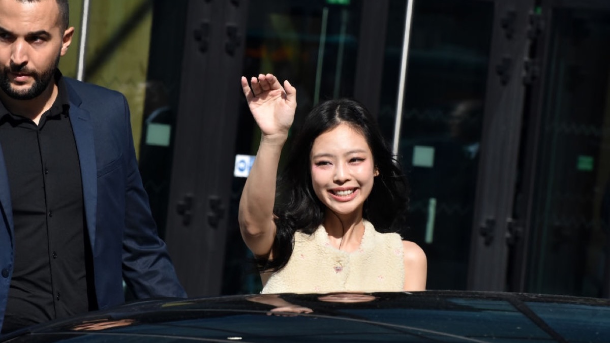BlackPink's Jennie waves to cameras while getting into a car.