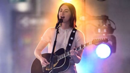 Gracie Abrams playing guitar and singing on stage.