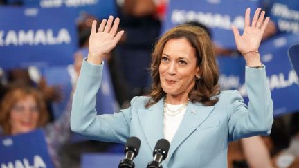 Kamala Harris raises her hands and smiles at a campaign event.