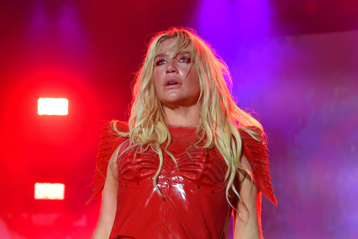 Kesha performs onstage, dressed in red