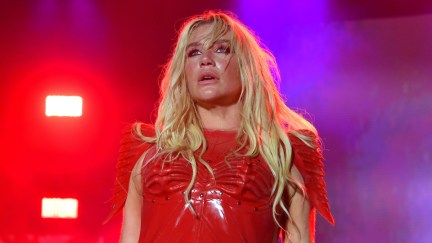 Kesha performs onstage, dressed in red