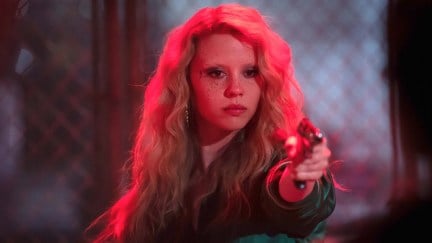 mia goth holding up a gun in maXXXine