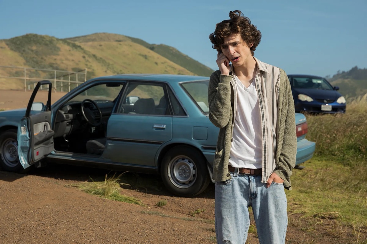 A young man talks on a cellphone in front of a car in "Beautiful Boy" 