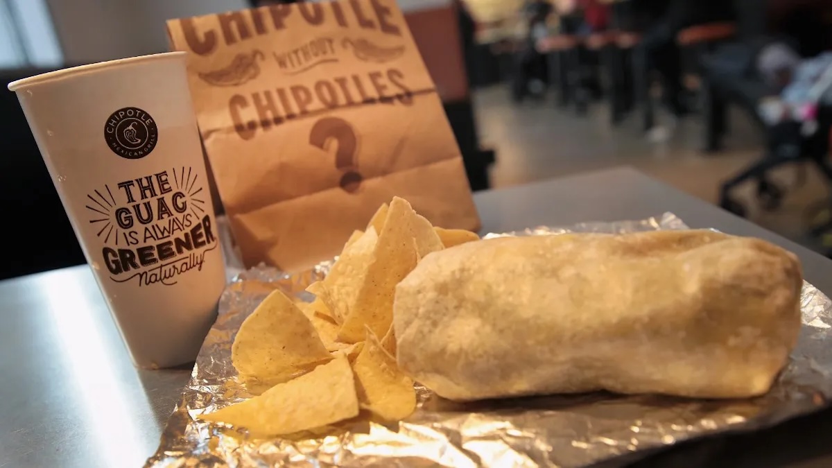 A Chipotle burrito meal with chips and a drink.