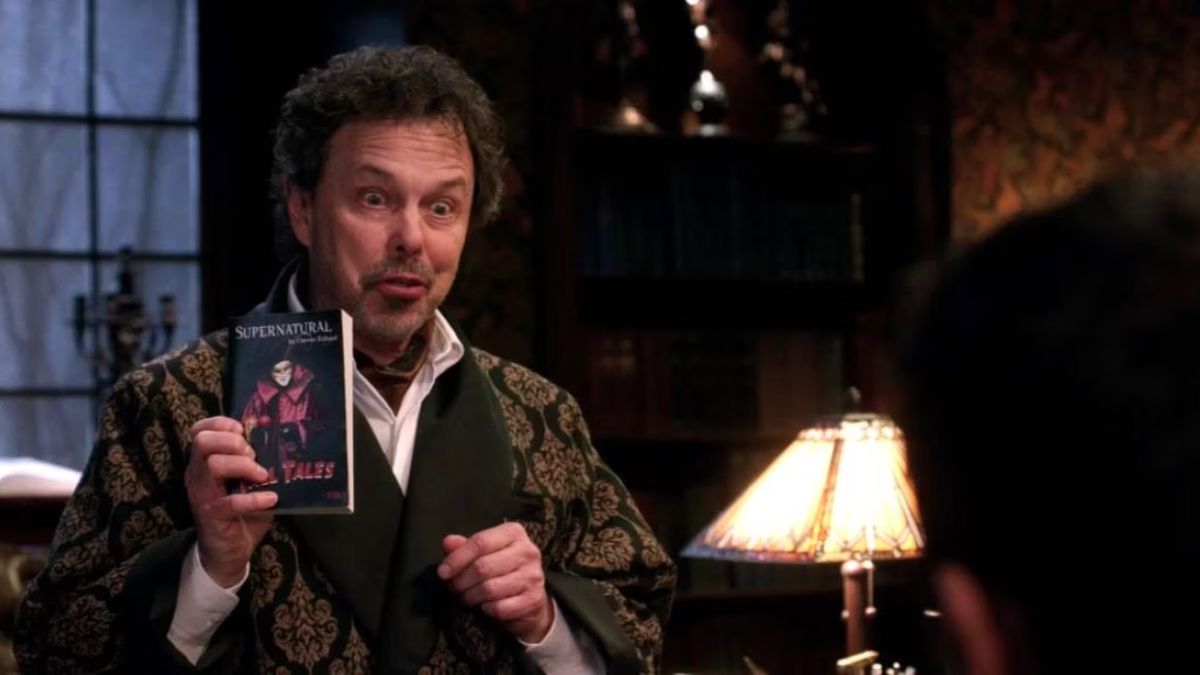 Curtis Armstrong as Metatron holds up a book in Supernatural season 9