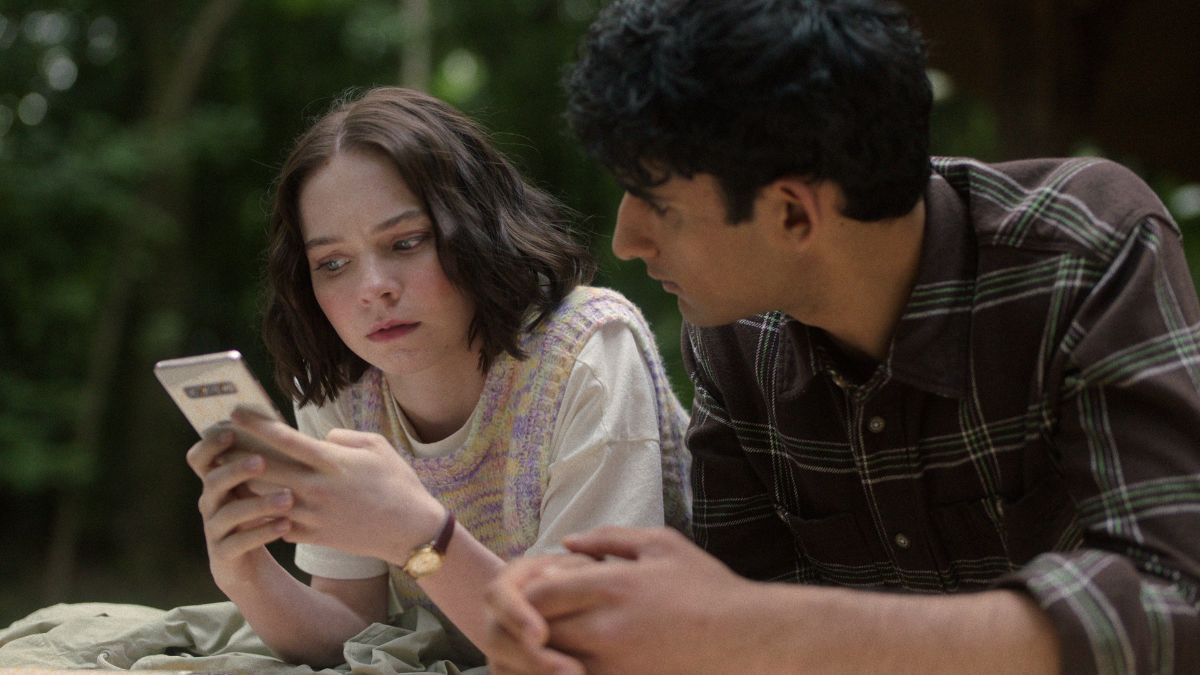 Emma Myers as Pip and Zain Iqbal as Ravi look into a phone in A Good Girls Guide to Murder