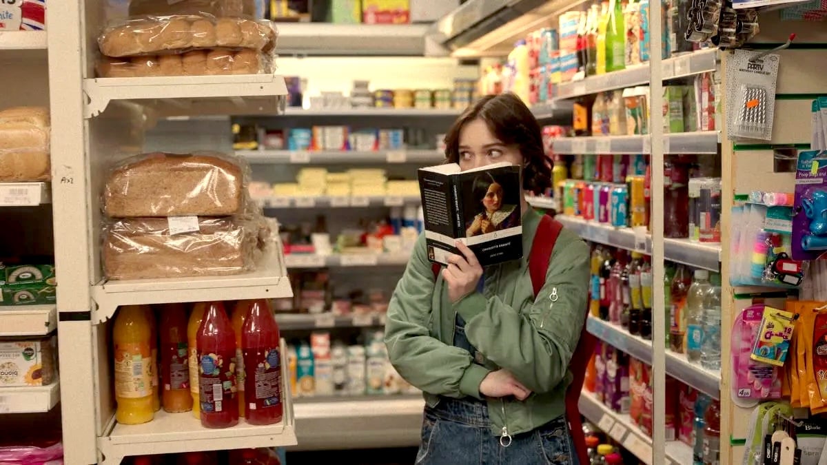 Emma Myers as Pip reads Charlotte Bronte's Jane Eyre in a supermarket in A Good Girl's Guide to Murder