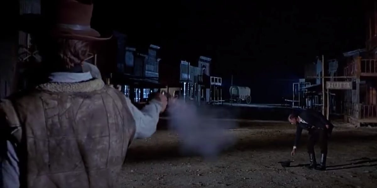 A gunslinger shoots a man on a dark street in "For A Few Dollars More"