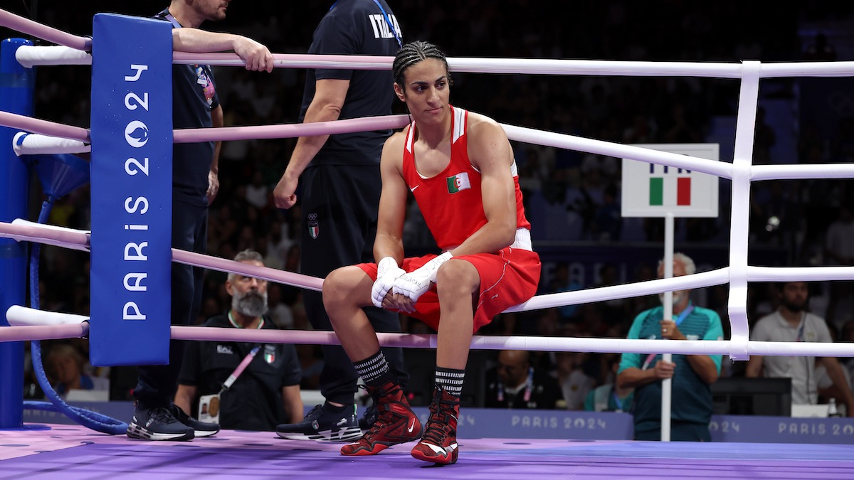 Imane Khelif sitting on the ropes of the Olympic boxing ring.