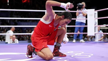 Imane Khelif kneels in the ring after defeating Ana Luca Hamori in a boxing match as the 2024 Olympics