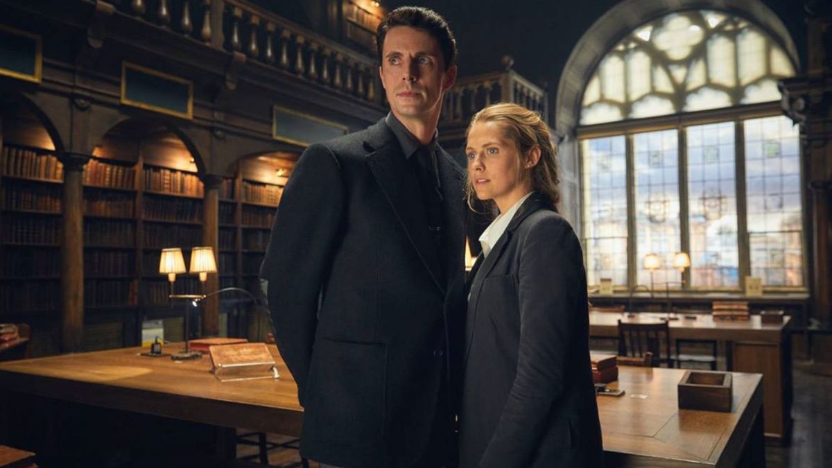 Matthew Goode as Matthew Clairmont and Teresa Palmer as Diana Bishop stand in the Bodleian Library in A Discovery of Witches