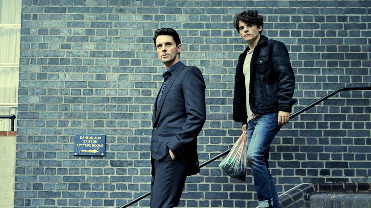 Matthew Goode as Matthew Clairmont and Edward Bluemel as Marcus Whitmore walk down a flight of stairs in A Discovery of Witches