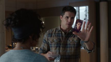 Robbie Amell as Nathan uses futuristic phone screen emanating from his palm as Andy Allo as Nora looks on in Upload season 3