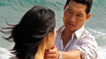 Image of Daniel Dae Kim as Jin and Yunjin Kim as Sun on ABC's 'Lost.' He is a Korean man with short, dark hair wearing a white button-down with red and grey stripes. We see Sun, a Korean woman with shoulder-length dark hair, from behind as he touches her chin and looks at her with concern. They are standing by the ocean.