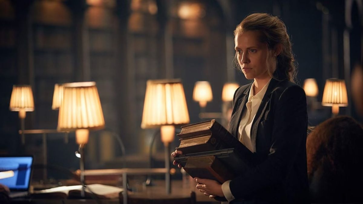 Teresa Palmer as Diana Bishop holding a book in A Discovery of Witches