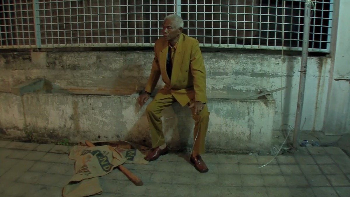 An old man sits in an alleyway in "The Act of Killing"