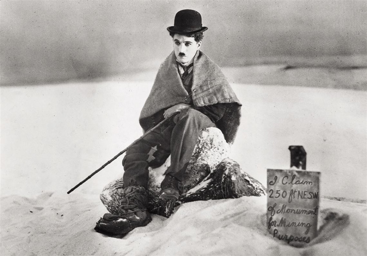 Charlie Chaplin sits in the snow wrapped in a blanket in "The Gold Rush"