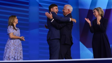 Tim Walz hugs his son, Guz Walz, as his daughter and wife look on at the DNC