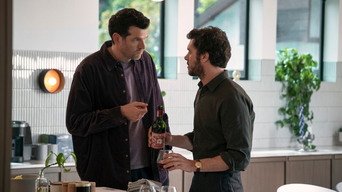 Timothy Simons as Sasha talks to Adam Brody as Noah as he is pouring a glass of wine in Nobody Wants This