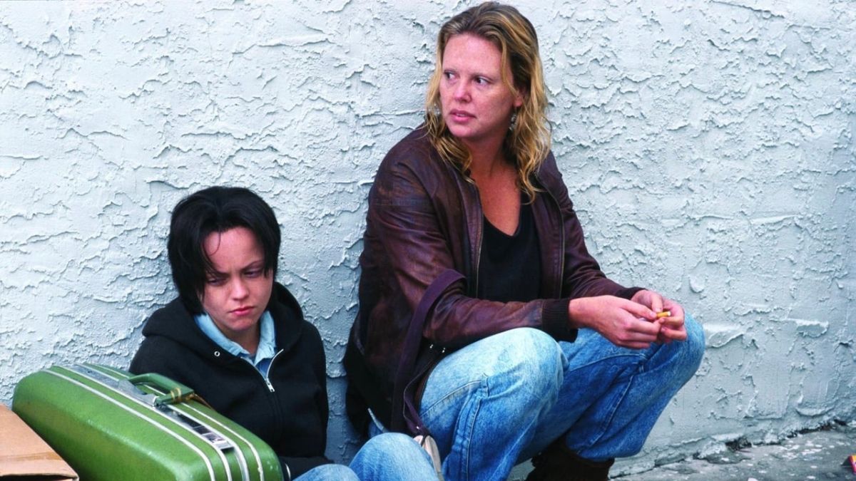 Charlize Theron as Aileen Wuornos crouching next to Christina Ricci's Selby Wall in Monster. 