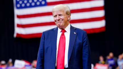 donald trump standing in front of a flag