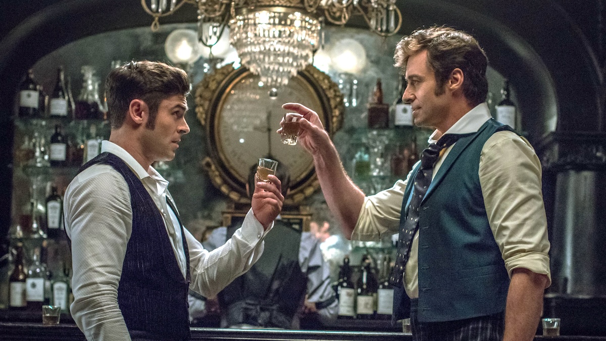 hugh jackman holding up a drink with zac efron