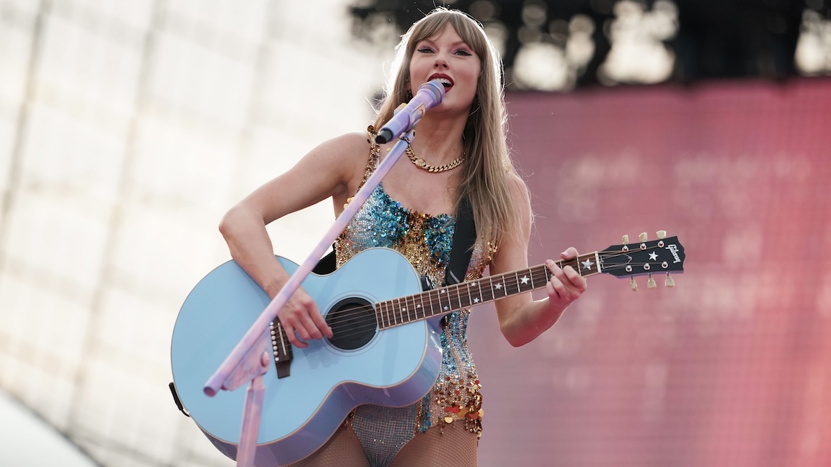 Taylor Swift standing with a guitar on stage