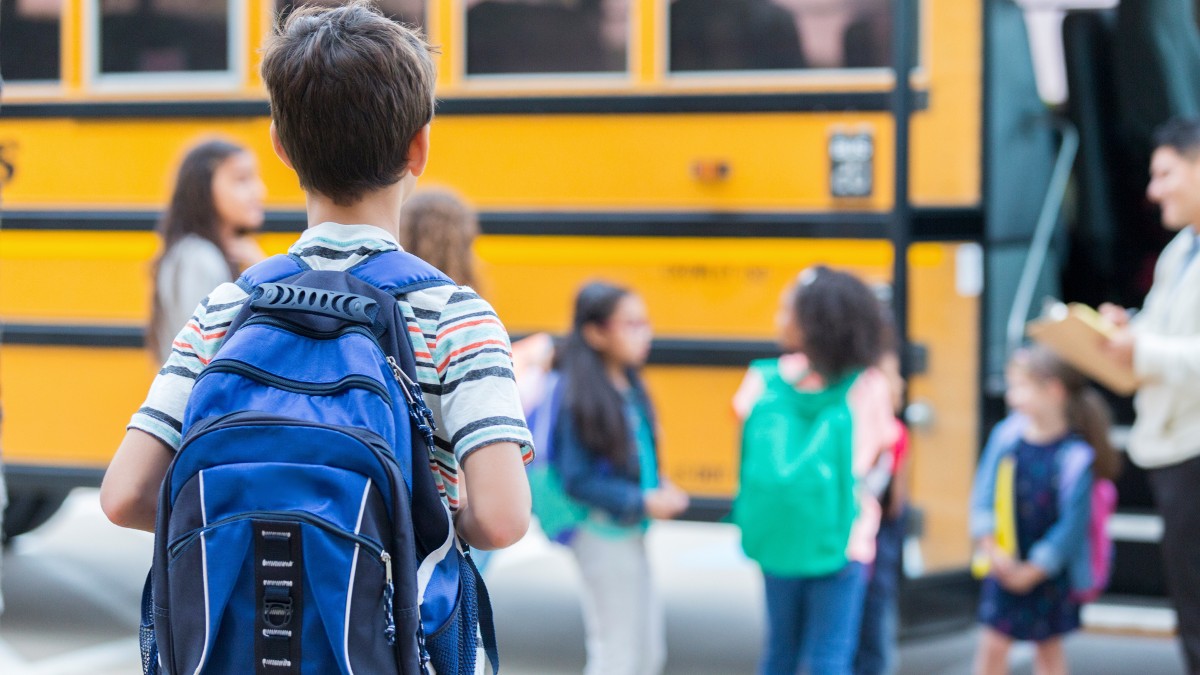 A boy with a backpack waits to board a school bus