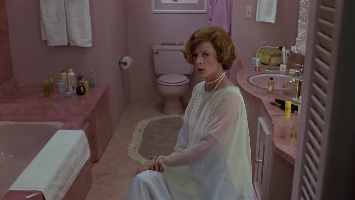 Maggie Smith sits in a pink bathroom