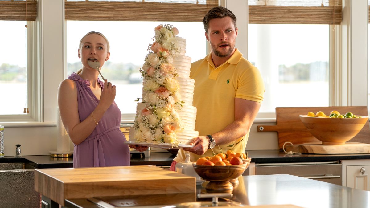 Dakota Fanning as Abby Winbury and Jack Reynor as Thomas Winbury hold a multi-tier wedding cake in The Perfect Couple