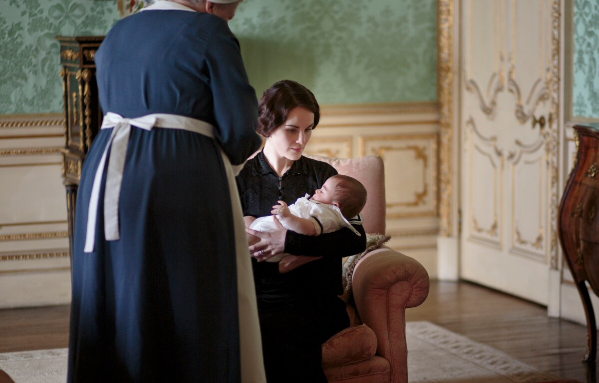 Lady Mary holds her baby while a nurse hovers nearby