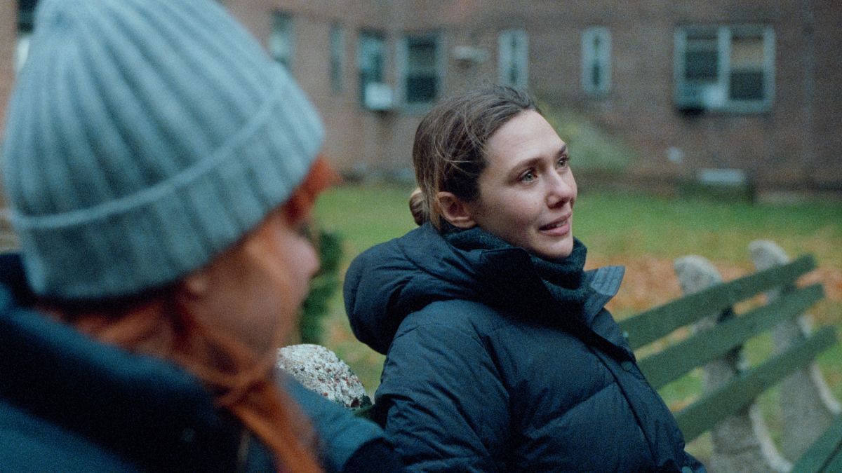 Elizabeth Olsen as Christina talks to Natasha Lyonne as Rachel outside on a bench in His Three Daughters