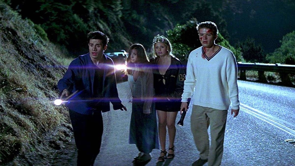 four teens hold a flashlight on a dark road