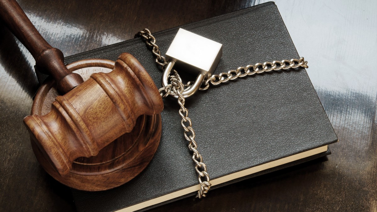 A judge gavel on top of a chained and padlocked book