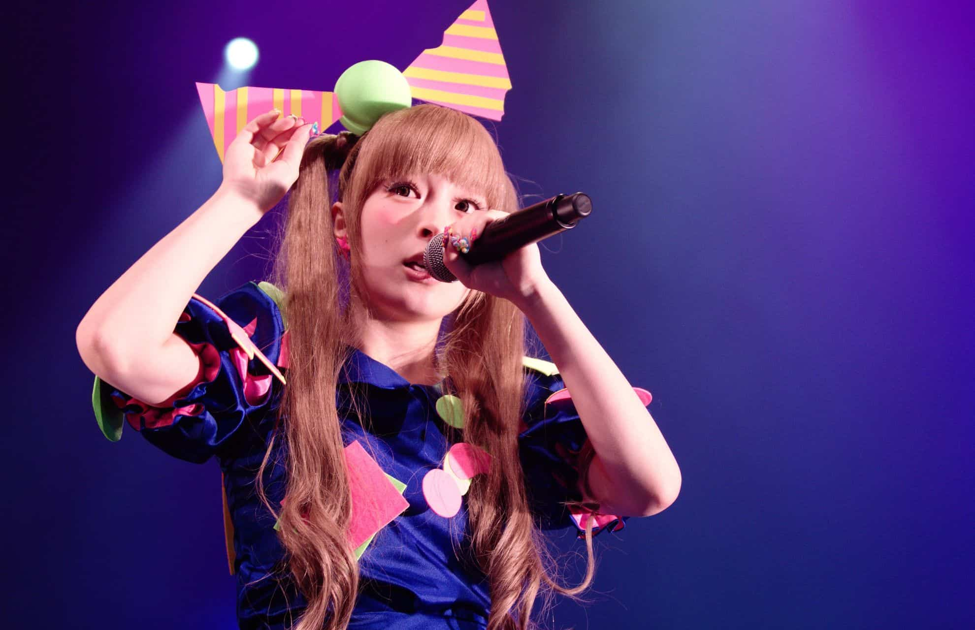 Kyary Pamyu Pamyu singing at Japan Expo with a ribbon on her head.