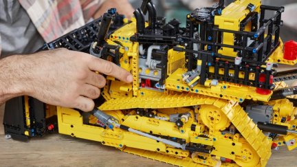 A man constructing a LEGO bulldozer