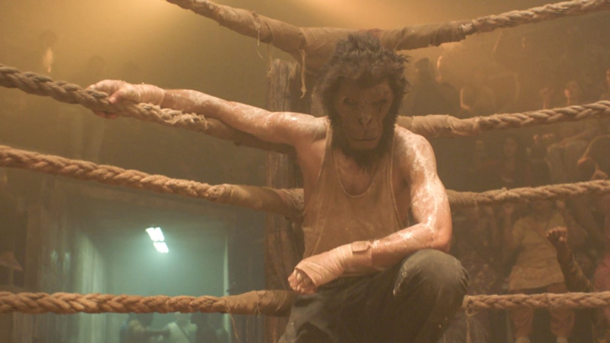 A boxer wearing a monkey mask crouches in the ring in "Monkey Man"