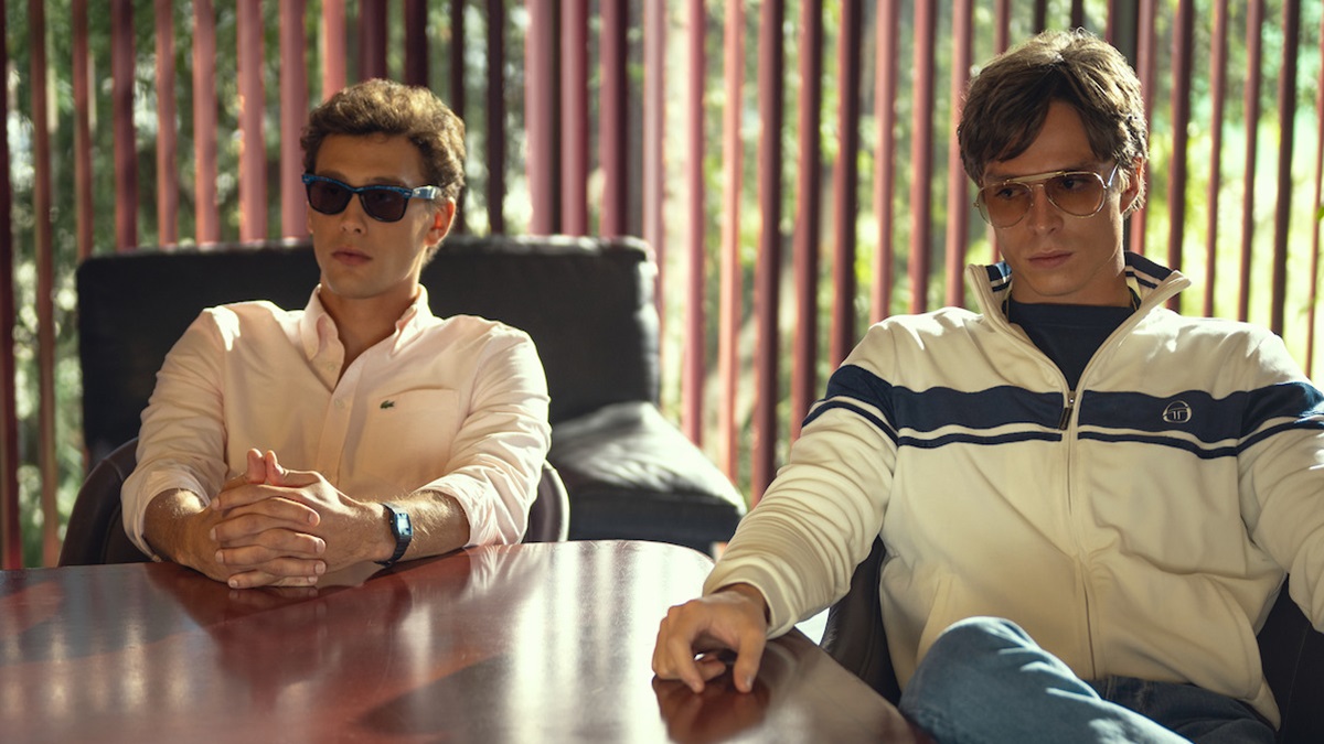 Lyle (Nicholas Alexander Chavez) and Erik (Cooper Koch) sit at a conference room table.