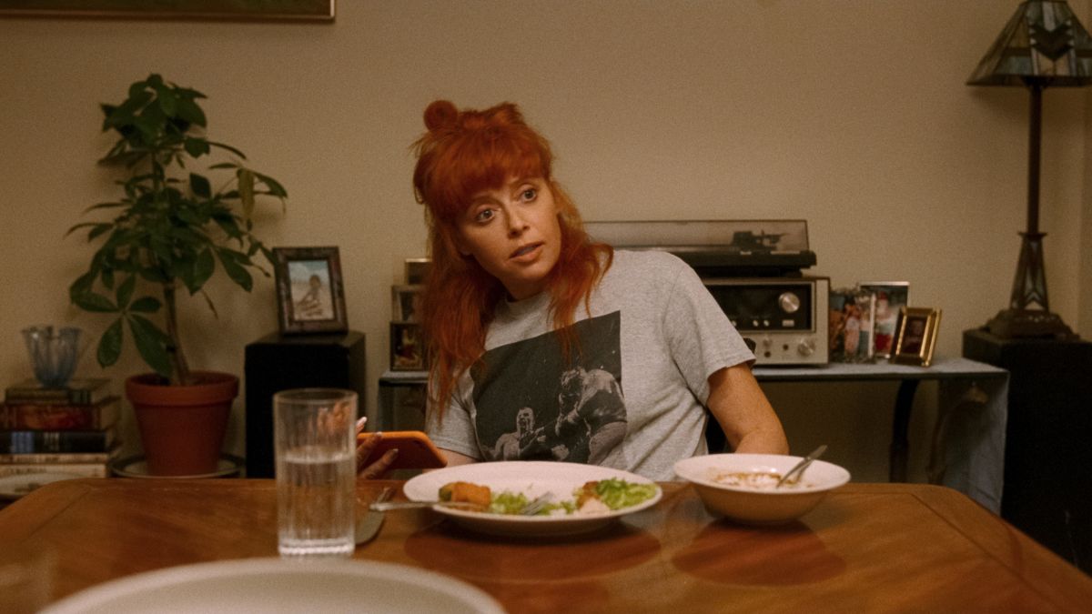 Natasha Lyonne as Rachel sits at the dining table in His Three Daughters