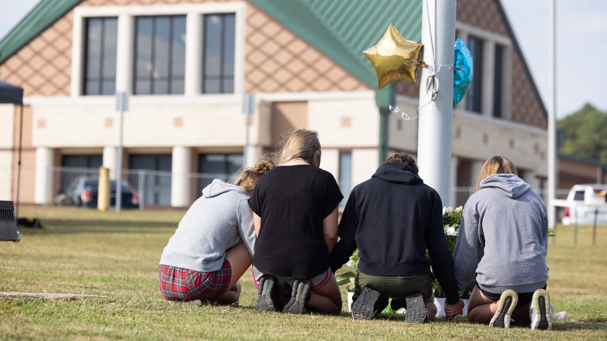 WINDER, GEORGIA - SEPTEMBER 5: Students kneel in front of a makeshift memorial in front of Apalachee High School on September 5, 2024 in Winder, Georgia. Two students and two teachers were shot and killed at the school on September 4, and a 14-year-old suspect, who is a student at the school, is in custody. (Photo by Jessica McGowan/Getty Images)