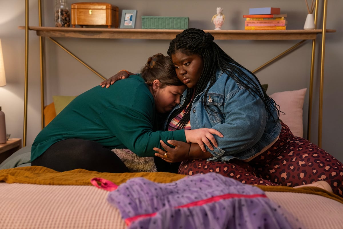 Still from Empire Waist shows Lenore and Kayla embracing on Lenore's bed