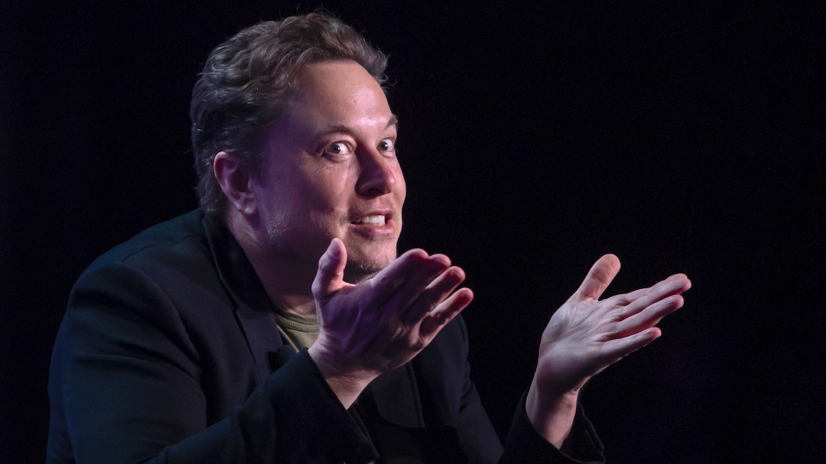 Elon Musk shrugs, wide-eyed.