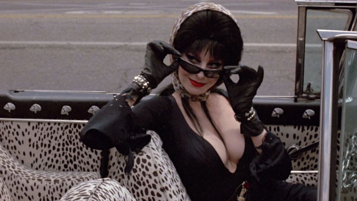 Cassandra Peterson peering down her sunglasses in Elvira: Mistress of the Dark.