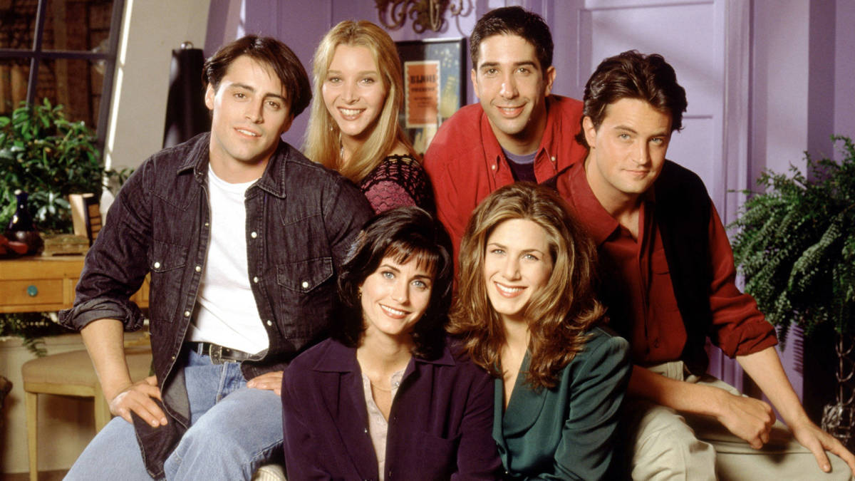 The cast of "Friends" sit together smiling