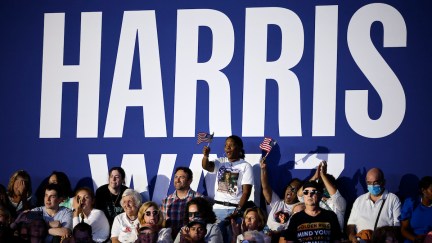 Kamala Harris supporters rally in front of a giant sign reading Harris Walz