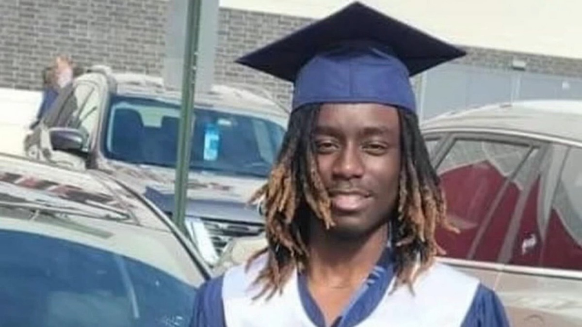 A young Black man (Javion Magee) smiles in a graduation cap and gown.