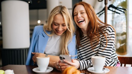 Women laughing while looking at phone.