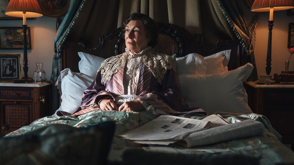 Anjelica Huston sitting up in an ornate bed in 'Towards Zero'